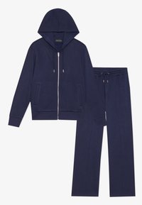 Fato de treino em polar navy com hoodie com fecho, apresentando bolsos laterais e calças com cordão. Textura macia e corte descontraído.