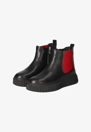Paire de bottines en cuir noir avec semelles à plateforme côtelées, panneaux latéraux élastiques rouges et fermetures éclair sur le côté intérieur.