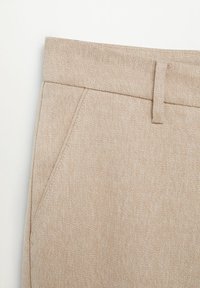 Pantalon beige texturé avec un motif chevron subtil ; doté d'une ceinture plate et de poches latérales pour un design minimaliste.
