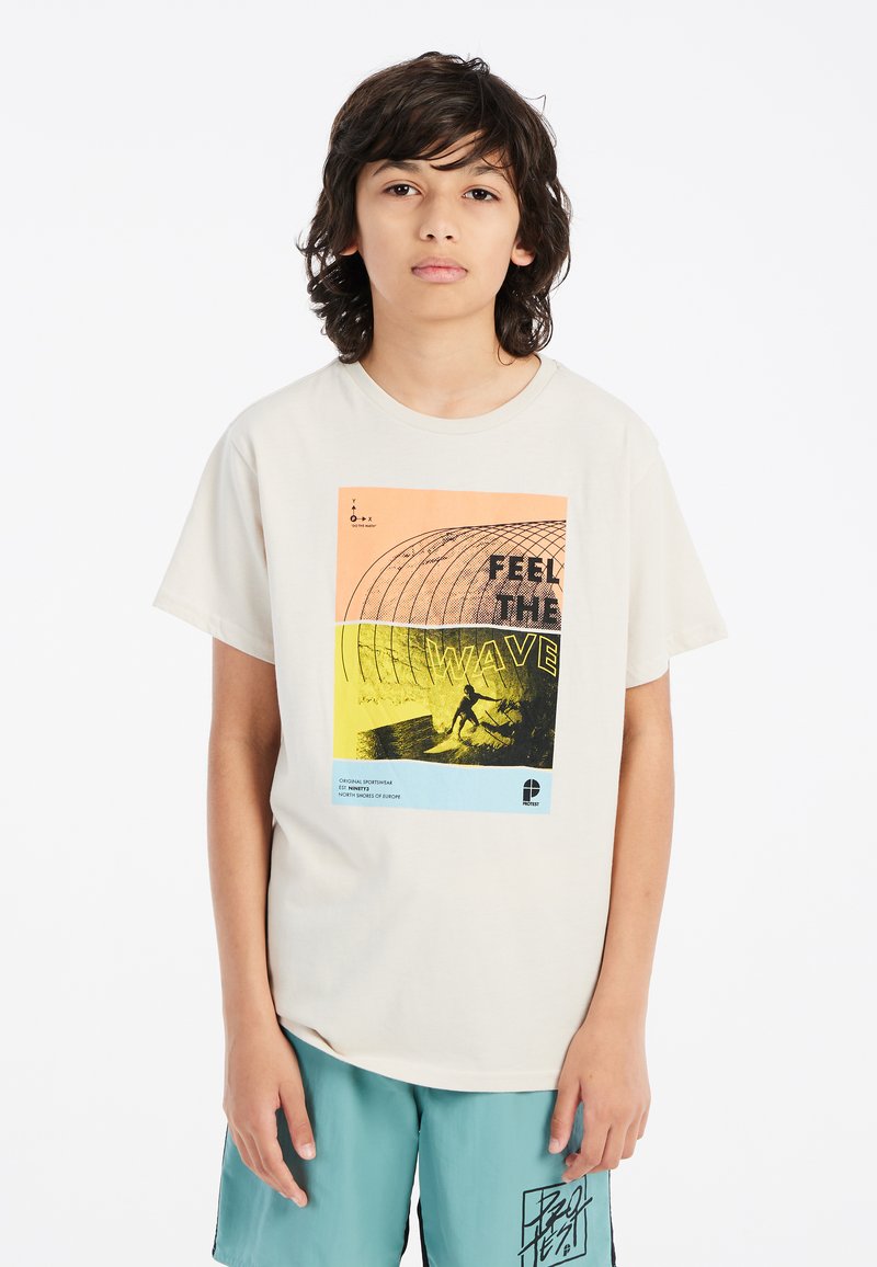 Camiseta de manga corta color crema con un estampado gráfico que incluye elementos en naranja, amarillo y negro, representando a un surfista y patrones geométricos.