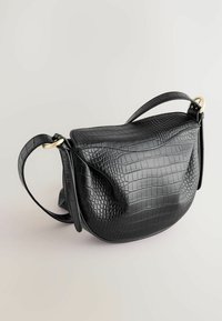 Sac à main en cuir noir embossé crocodile avec une forme incurvée, une seule anse supérieure et des accents en métal doré. Texture lisse sur l'ensemble.