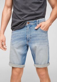 Vaaleansiniset farkkushortsit, joissa on kääntöhelma, viisi taskua, napitettava suljenta ja hieno haalistuminen. Yhdistetty tummanharmaaseen paitaan.