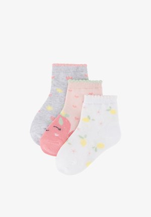Tres pares de calcetines para bebé en colores pastel: gris con corazones, rosa con una cara sonriente de manzana y blanco con limones amarillos.