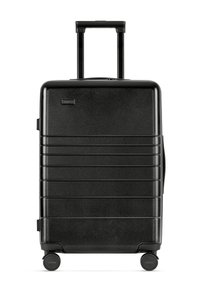 Black hard-shell suitcase with a textured finish, vertical grooves, retractable handle, and four wheels for mobility.