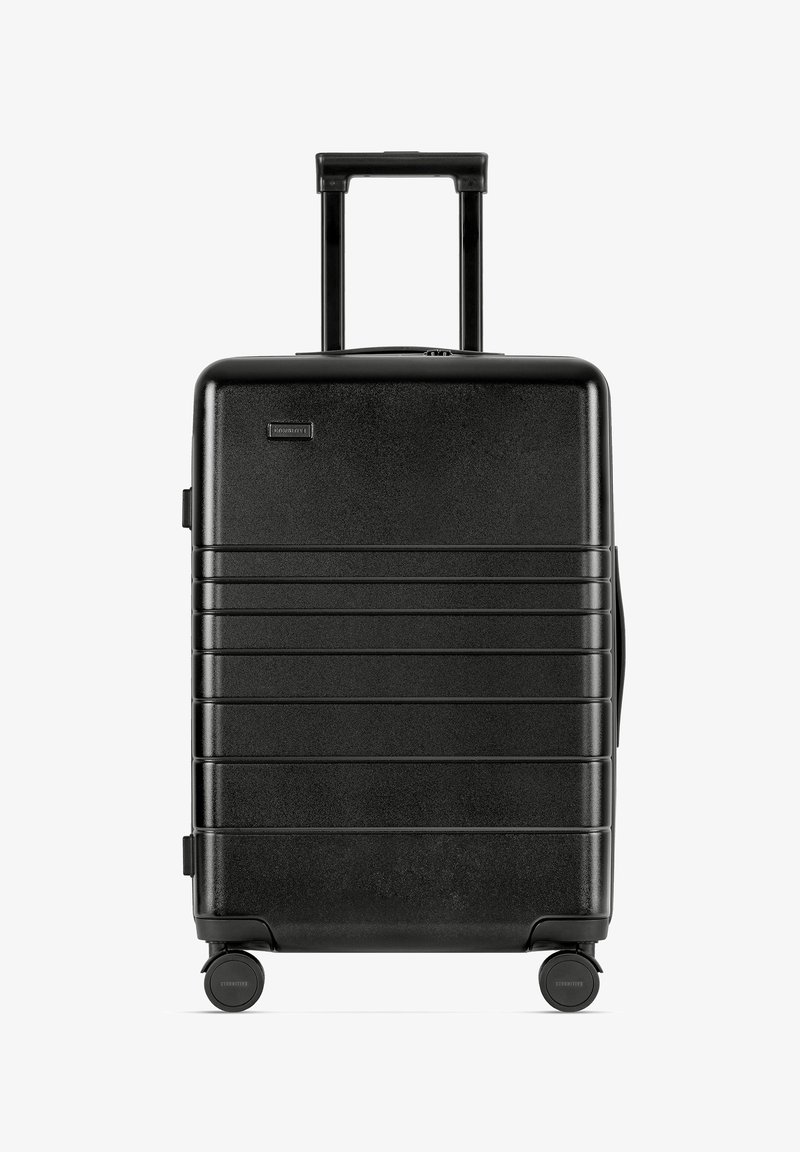 Schwarzer Hartschalenkoffer mit strukturiertem Finish, vertikalen Rillen, ausziehbarem Griff und vier Rädern für Mobilität.