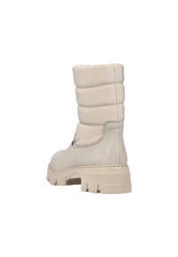 Botas de invierno beige con parte superior acolchada, suela de goma y acabado texturizado. Cuenta con una puntera redondeada y detalles de costura reforzada.