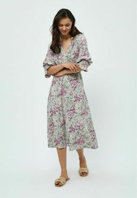 Robe maxi fleurie avec un décolleté en V, manches courtes volumineuses, motifs verts et violets sur un fond clair, fabriquée en tissu léger.