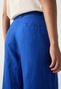 Royal blue wide-leg trousers made from lightweight fabric; includes a back pocket and features a smooth texture.