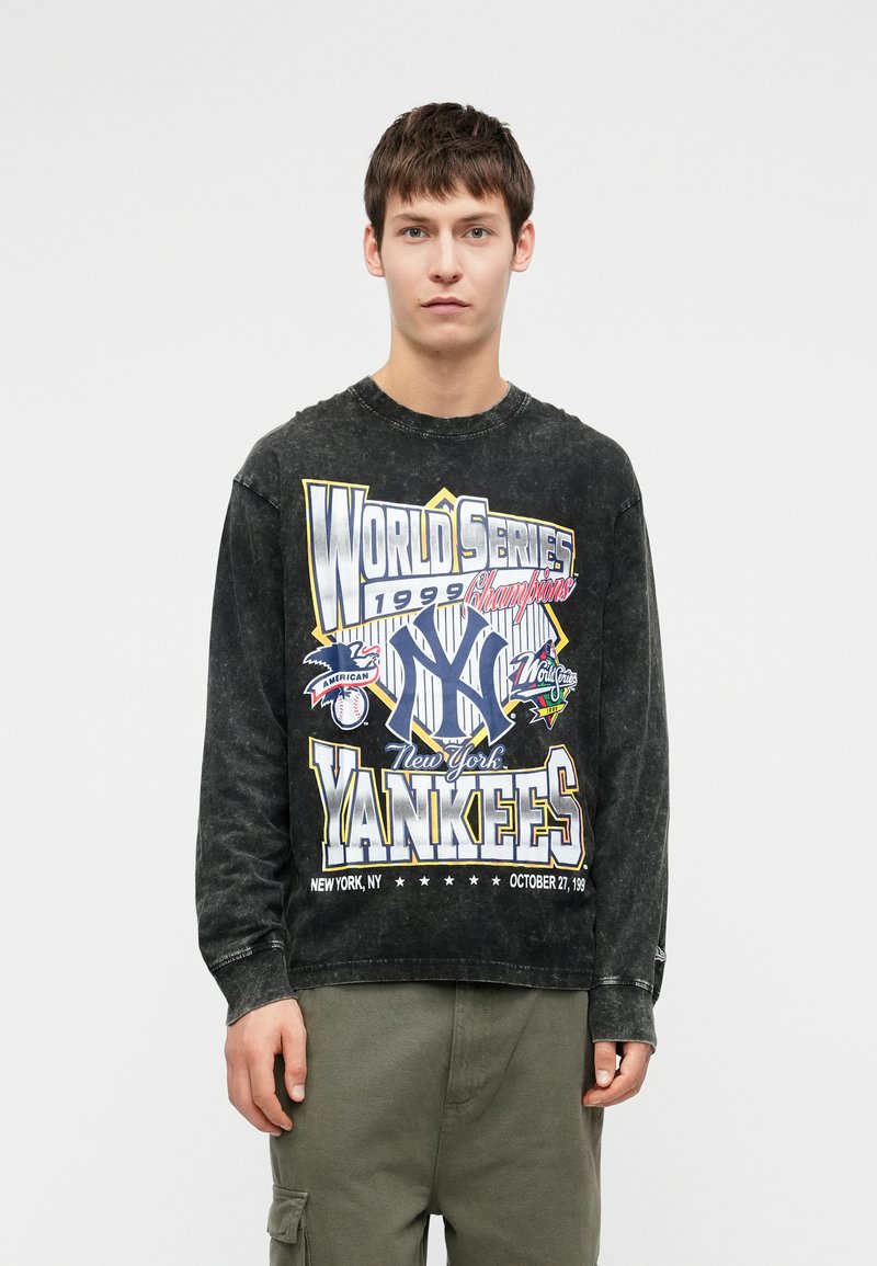 Juodas ilgomis rankovėmis medvilninis marškinėlis su retro Yankees grafiką, su spalvingu tekstu ir sporto motyvais. Kasdienis siluetas, banguota apykaklė.
