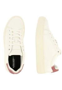 Witte canvas sneakers met ronde neus, platte rubberen zool en vetersluiting. Rode accent op de hiel, gestructureerd zijdetail en zwarte binnenzool.