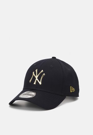 Navy baseball cap with a gold New York Yankees logo, structured design, curved brim, and adjustable closure. Textured fabric.