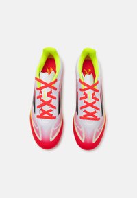 Zapatillas deportivas con un diseño ligero, parte superior de sintético blanco, acentos en rosa brillante, una franja negra y detalles en amarillo neón.