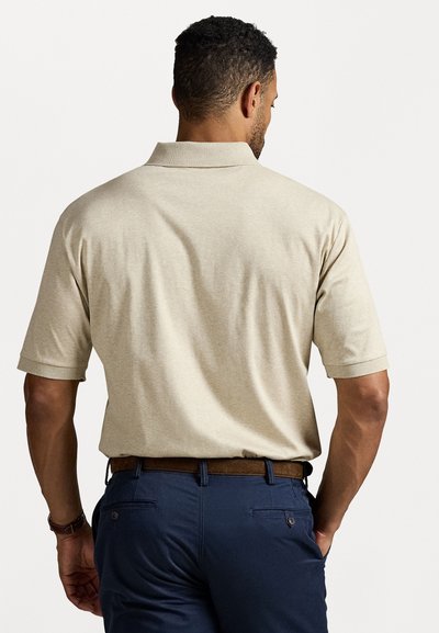 Cămașă polo bej cu mâneci scurte și guler clasic, asociată cu pantaloni bleumarin și o curea maro. Textură netedă, croială casual.