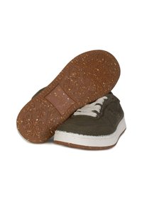 Sneakers in tela verde oliva con suola in gomma bianca e suola texturizzata marrone con motivi floreali. I lacci sono di un grigio chiaro.