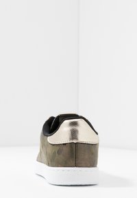 Sneakers w kamuflażu z teksturowaną oliwkowozieloną cholewką, czarnym materiałowym kołnierzem i błyszczącym złotym metalicznym akcentem na pięcie na białej podeszwie.