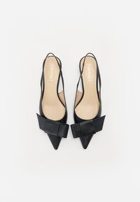 Svarte skinn slingback-hæler med spiss tå, prydet med en stor bueakkent på utsiden og en beige innvendig fôr.