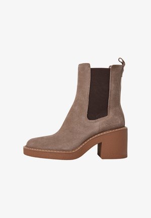 Bottine en suède marron avec des panneaux latéraux élastiques, un bout carré et un talon bloc texturé marron. Présente une languette en boucle pour un enfilage facile.