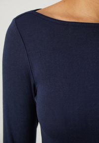 Navy blauwe top met lange mouwen, gemaakt van ribstof, met een brede halslijn en een soepele textuur, met minimale stiksels.