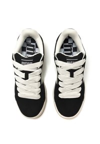 Zapatillas de ante negras con cordones blancos, un collar acolchado y un patrón de plantilla de cuadros. La suela es de goma y está ligeramente elevada.