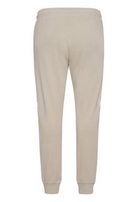 Beige Sweatpants mit elastischem Bund, schmalem Bein-Design, glatter Textur und weißen seitlichen Akzenten. Keine sichtbaren Taschen.