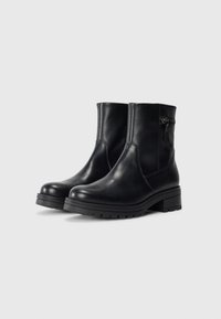 Botas de cuero negro hasta el tobillo con un acabado suave, punta redonda y tacón cuadrado. Presentan una cremallera lateral y un sutil detalle de costura.