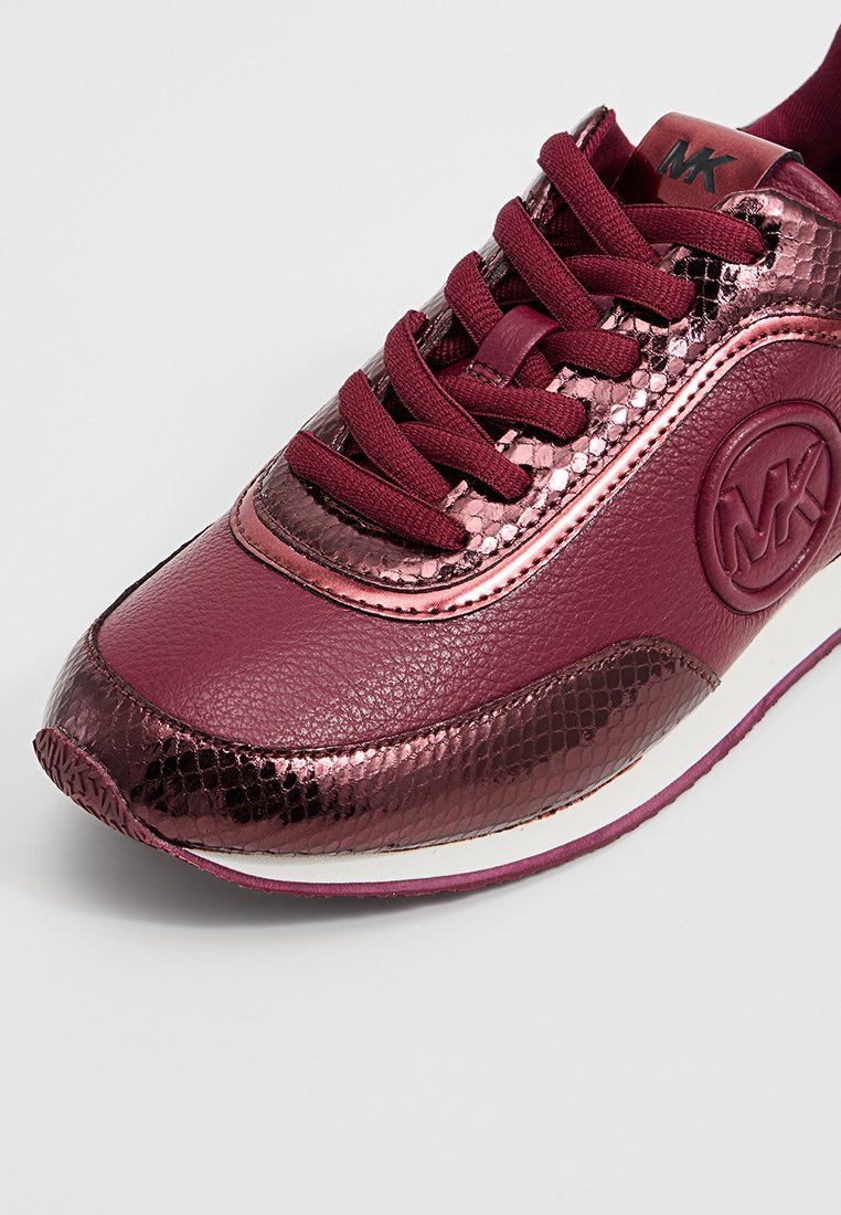 Sneaker in pelle bordeaux con texture in pitone metallico, lacci e logo circolare in rilievo sul lato.