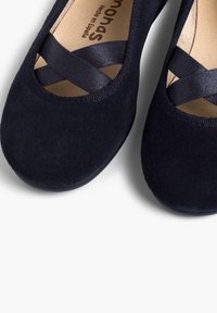 Ballerines bleu marine en daim souple, présentant un bout arrondi et des sangles en satin croisées, avec une doublure intérieure lisse.