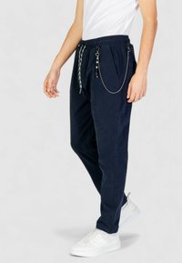 Pantaloni jogger navy in tessuto morbido, con vita elastica, tasche laterali e dettaglio a catena con perline e clip.