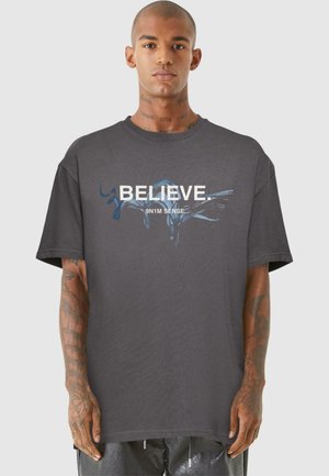 Grå grafisk t-shirt med teksten "BELIEVE." og et abstrakt design i blå. Kortærmet, crew neck, afslappet pasform og blødt stof.