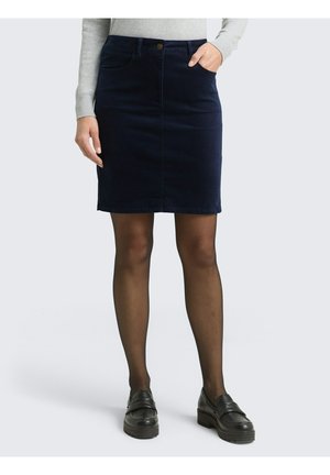 Marineblauwe corduroy rok met een rechte snit, voorzakken en een sluiting met knopen aan de voorkant. Gepaard met zwarte schoenen en doorzichtige panty's.