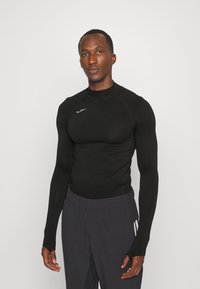 Schwarzes, langärmliges Sportshirt mit slim fit und Rundhalsausschnitt, aus glattem Stoff mit kleinem Logo auf der Brust.