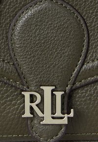 Detail tmavě zelené kožené kabelky s výrazným kovovým logem "RLL" a texturovaným povrchem s kontrastním šitím.