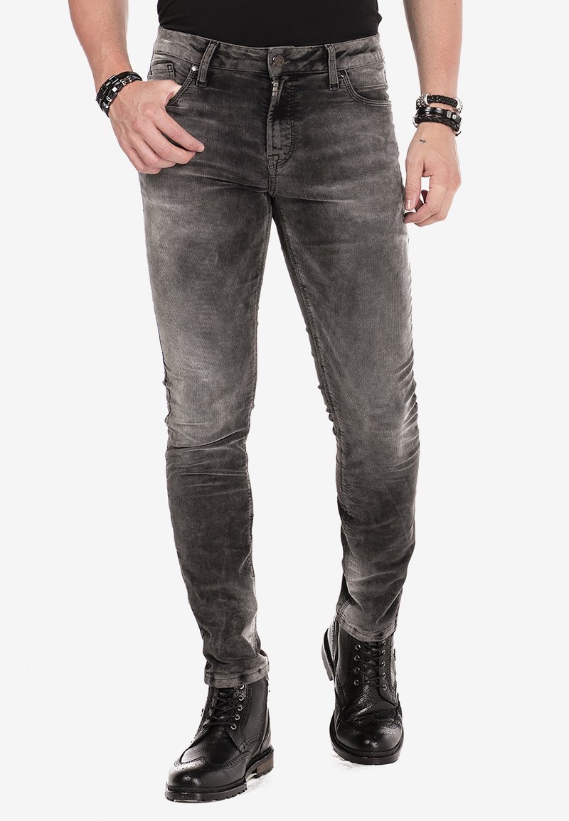 Jean gris slim avec une texture délavée, design à cinq poches et braguette zippée. Associé à des bottes noires à lacets et un haut noir ajusté.