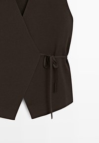 Dunkelbraunes ärmelloses Wickeltop mit seitlicher Bindung und asymmetrischem Saum aus geripptem Strickstoff.