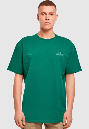 Grøn bomulds t-shirt med korte ærmer, rund halsudskæring og trykt tekst på forsiden. Materialet ser blødt ud med en glat overflade.