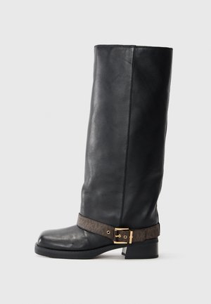 Bota de cuero negro hasta la rodilla con punta redonda, que presenta una correa de patrón marrón y un detalle en metal dorado cerca del tobillo.