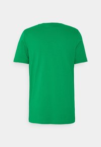En enfärgad grön t-shirt med kort ärm visas bakifrån på en vit bakgrund.