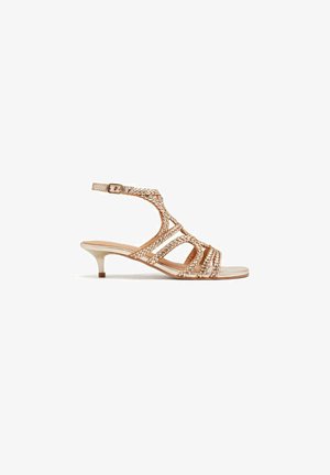 Sandalias de tacón beige con tiras, detalles trenzados y correa al tobillo; tacón de kitten bajo y diseño de punta abierta. Acabado de material suave.