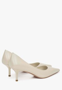 Béžové kožené lodičky s špičatou špičkou, nízkým stiletto podpatkem a výřezy na bocích. Hladká textura a minimalistický design.