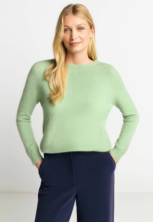 Light green wool sweater with a crew neck and long sleeves, featuring a soft texture and ribbed cuffs, worn with navy trousers.