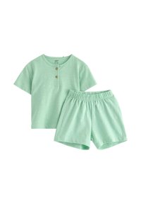 Miętowy t-shirt z krótkim rękawem i dwoma guzikami, w komplecie z elastycznymi spodniami, oba wykonane z miękkiej tkaniny.