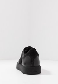 Czarne skórzane sneakersy z zamszowymi akcentami, niskoprofilowy design, okrągły nos i gumowa podeszwa. Posiadają przeszyty tył i markowe piętki.