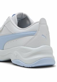 Scarpa sportiva bianca e azzurra chiaro con tomaia in pelle testurizzata, colletto imbottito e un design della suola ondulato. Presenta il logo Puma sul tallone.