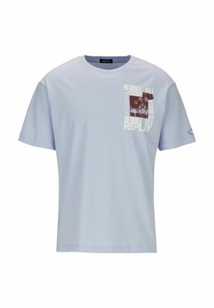 T-shirt bleu clair à manches courtes avec un motif devant à droite représentant des palmiers et le texte "Deep Vibes Replay No Control" en blanc et marron.