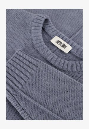 Gray knit sweater featuring a ribbed crew neckline and sleeve cuffs, with a textured pattern and a labeled tag. Soft, wool-like material.