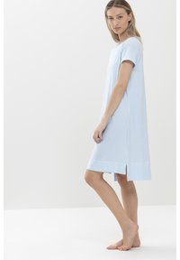 Robe rayée bleu clair avec des manches courtes, coupe décontractée, fentes latérales et un ourlet qui tombe au-dessus du genou. Texture de tissu douce.