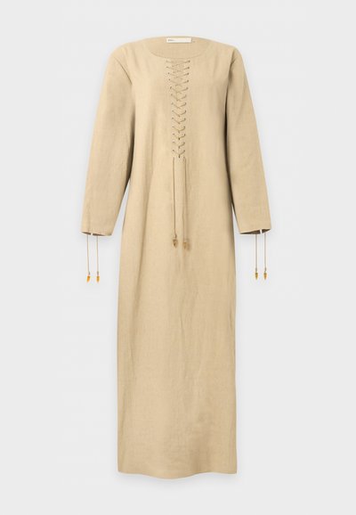 Longue robe beige avec manches longues, détail à lacets sur le devant, et cordons pendants des manches et du laçage central.