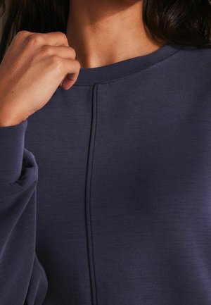 Marineblauwe sweatshirt met een ronde hals, zichtbare stikseldetails en lange mouwen. Zacht, textuurgevoelig stof met een relaxte pasvorm.