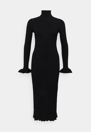 Robe en tricot noir à côtes avec un col haut, des manches longues et des poignets évasés, présentant une silhouette ajustée et une longueur mi-mollet.