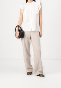 Hvid, rynket bluse med knaplukning; beige, bredbenede bukser; sort håndtaske; loafers med leopardprint; glatte teksturer og lette stoffer.